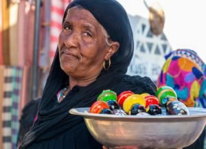 nubian woman holding a bowl full of hand made wooden articles