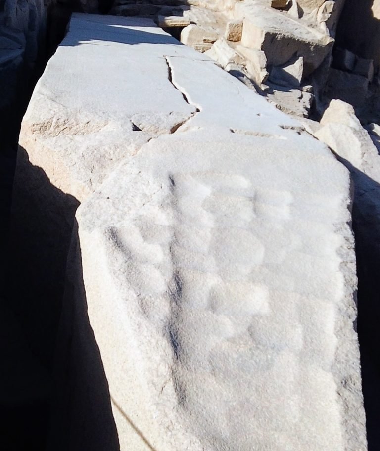 unfinished obelisk still in the rock quarry, in the foreground you can see chisel marks. in the center of the photo moving towards the top you can see a crack.